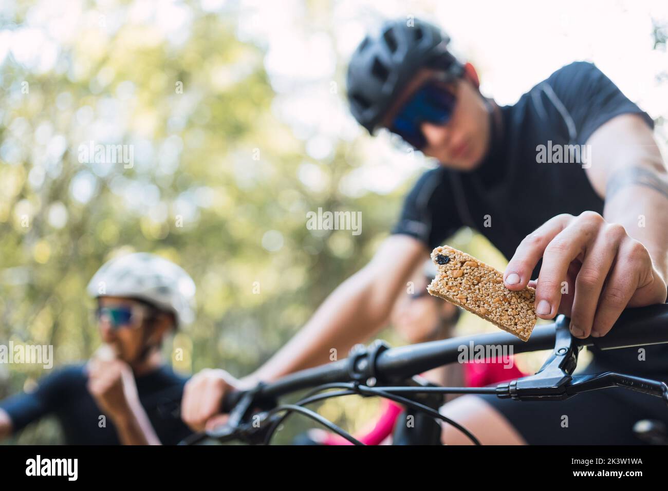 Von unten von Sportlern in Helmen mit Müsliriegel auf Fahrrädern während des Trainings bei Tageslicht Stockfoto