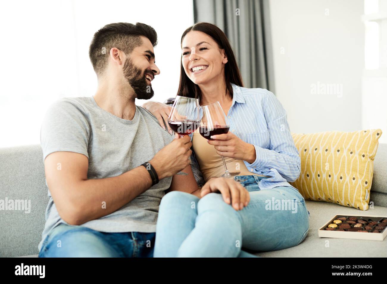 Porträt eines hübschen jungen Paares, das zu Hause auf dem Sofa zusammen Wein trinkt Stockfoto