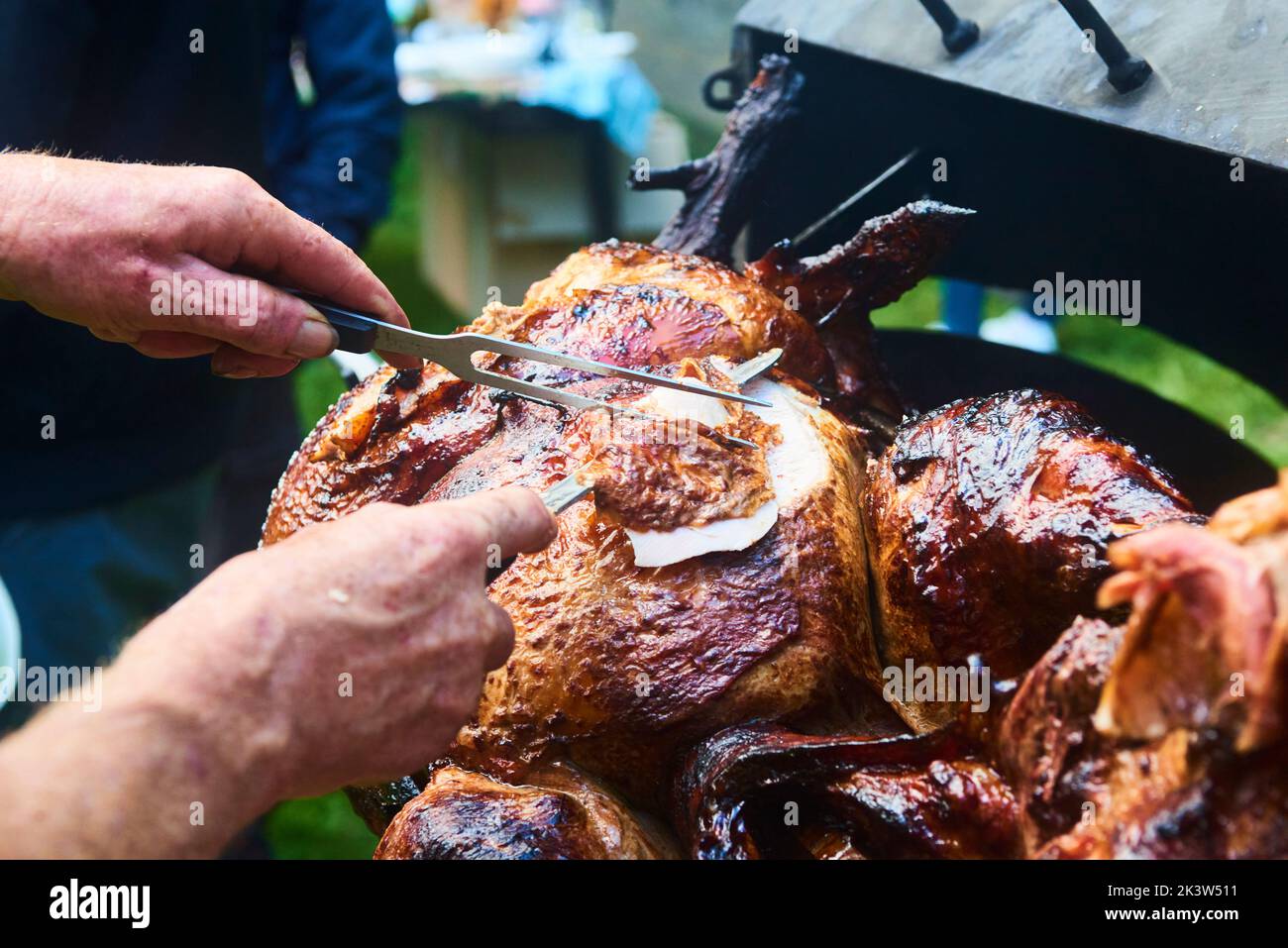 Der Koch schneidet das ganze gegrillte Schweinefleisch für Steaks mit einem Messer. Vom Schwein gegrillte traditionelle Kohle und Feuer. Das kleine Ferkel wird ganz auf einem offenen Feuer geröstet Stockfoto