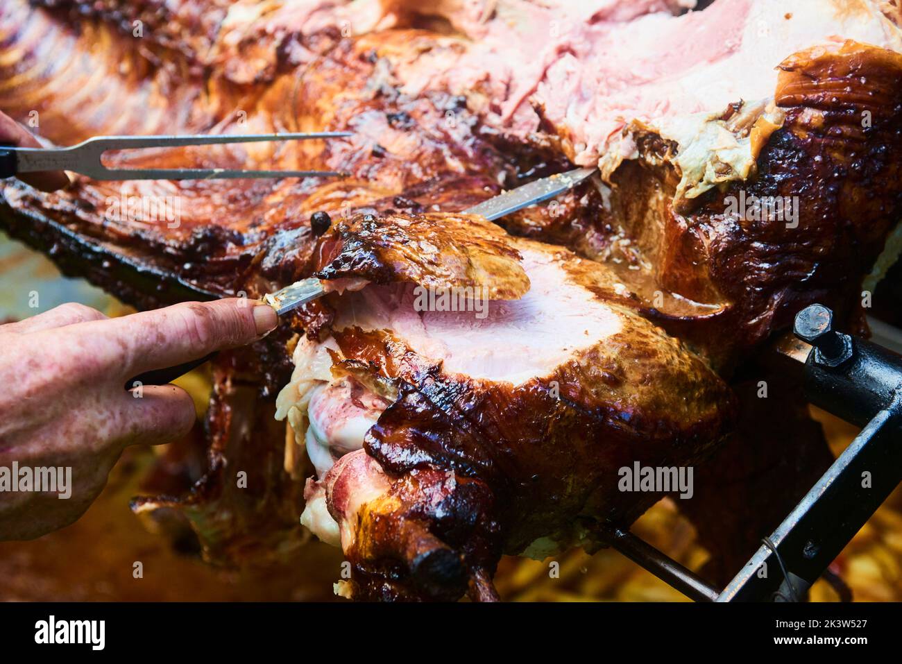 Der Koch schneidet das ganze gegrillte Schweinefleisch für Steaks mit einem Messer. Vom Schwein gegrillte traditionelle Kohle und Feuer. Das kleine Ferkel wird ganz auf einem offenen Feuer geröstet Stockfoto