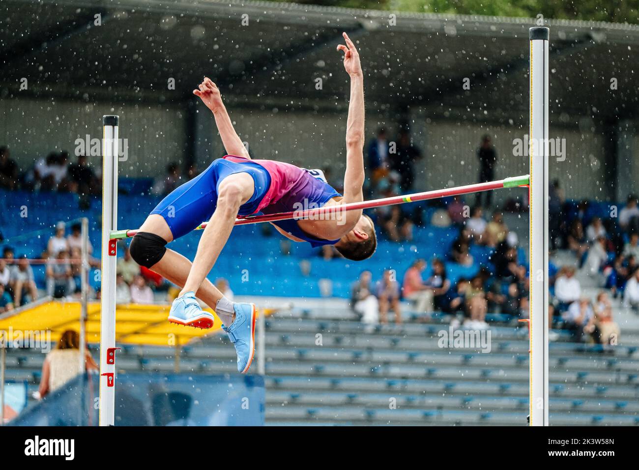 Männlicher Athlet Hochsprung im Regen Stockfoto