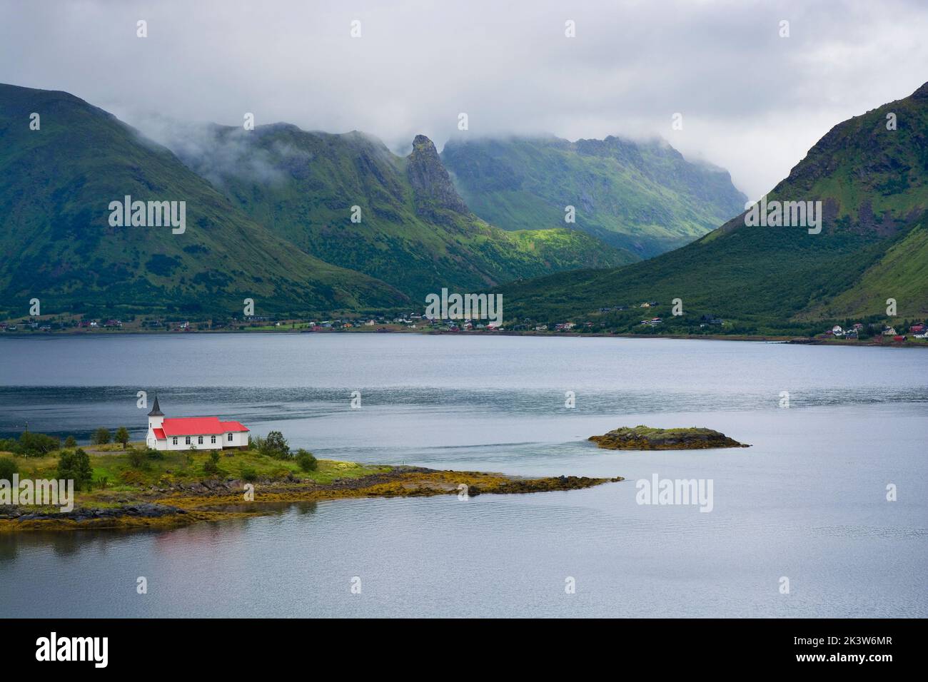 Blick auf den Austnesfjorden mit der Sildpollnes Kirche auf die bewölkten Berge, Lofoten, Norwegen Stockfoto
