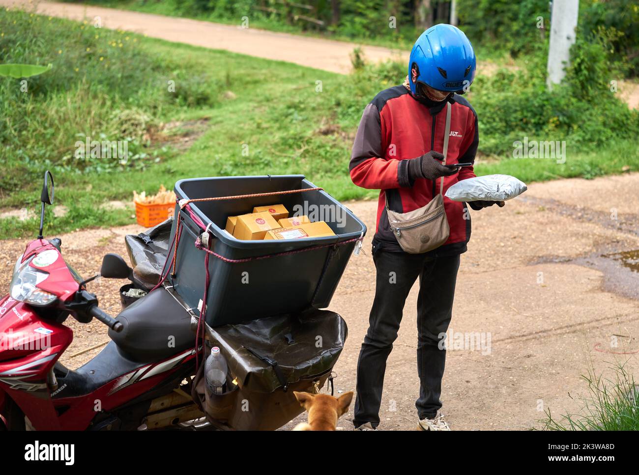 Ein Motorradkurier liefert Pakete in einem ländlichen Gebiet. Stockfoto