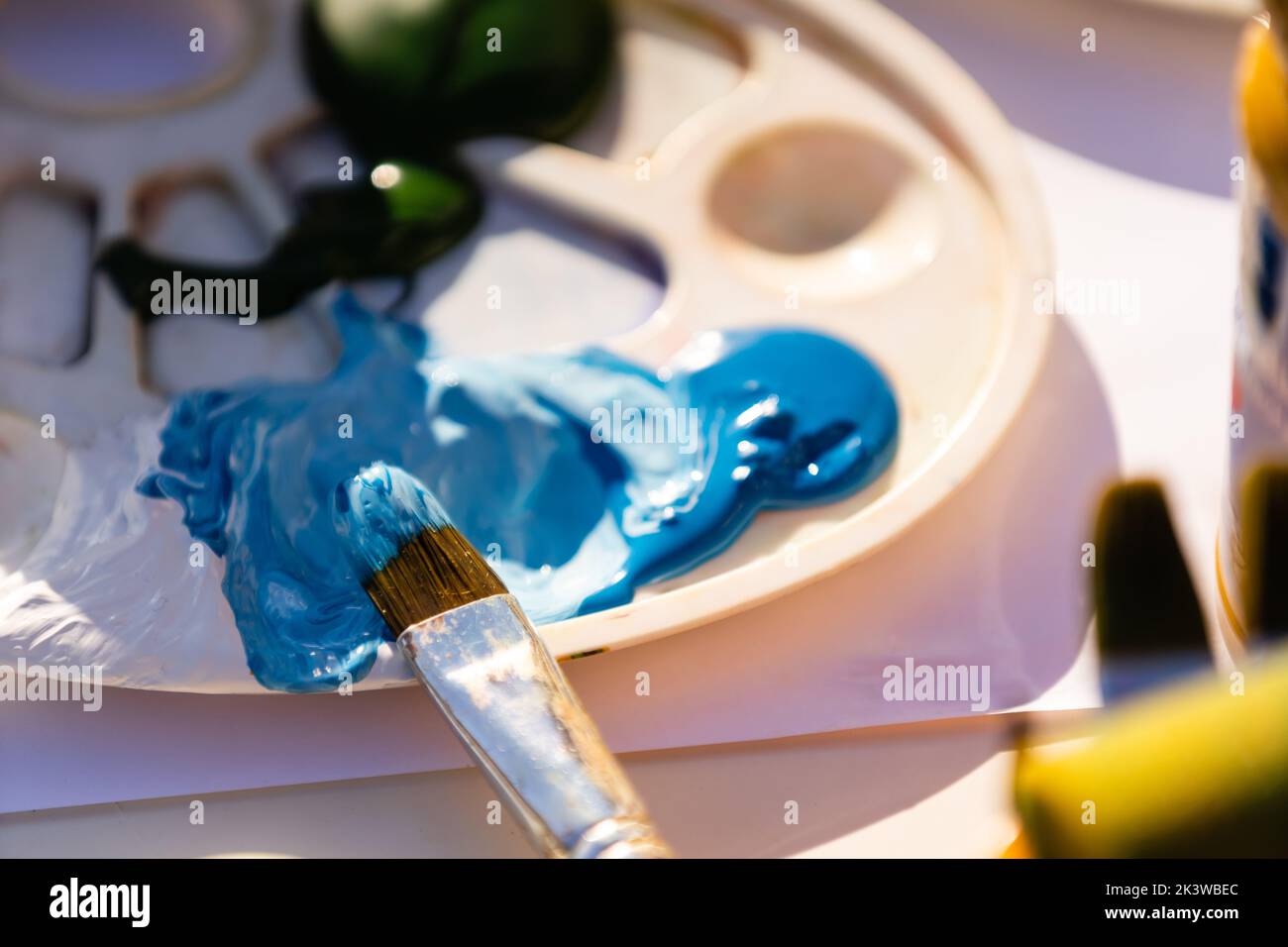 Farben und Pinsel im Prozess der Arbeit, Palette mit gemischten Farben. Stockfoto