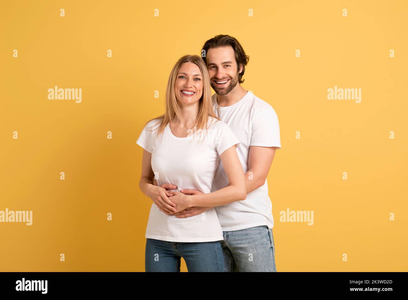 Liebe, Familienbeziehung und Romantik. Lächelnder junger kaukasischer Mann umarmt Frau in weißen T-Shirts Stockfoto