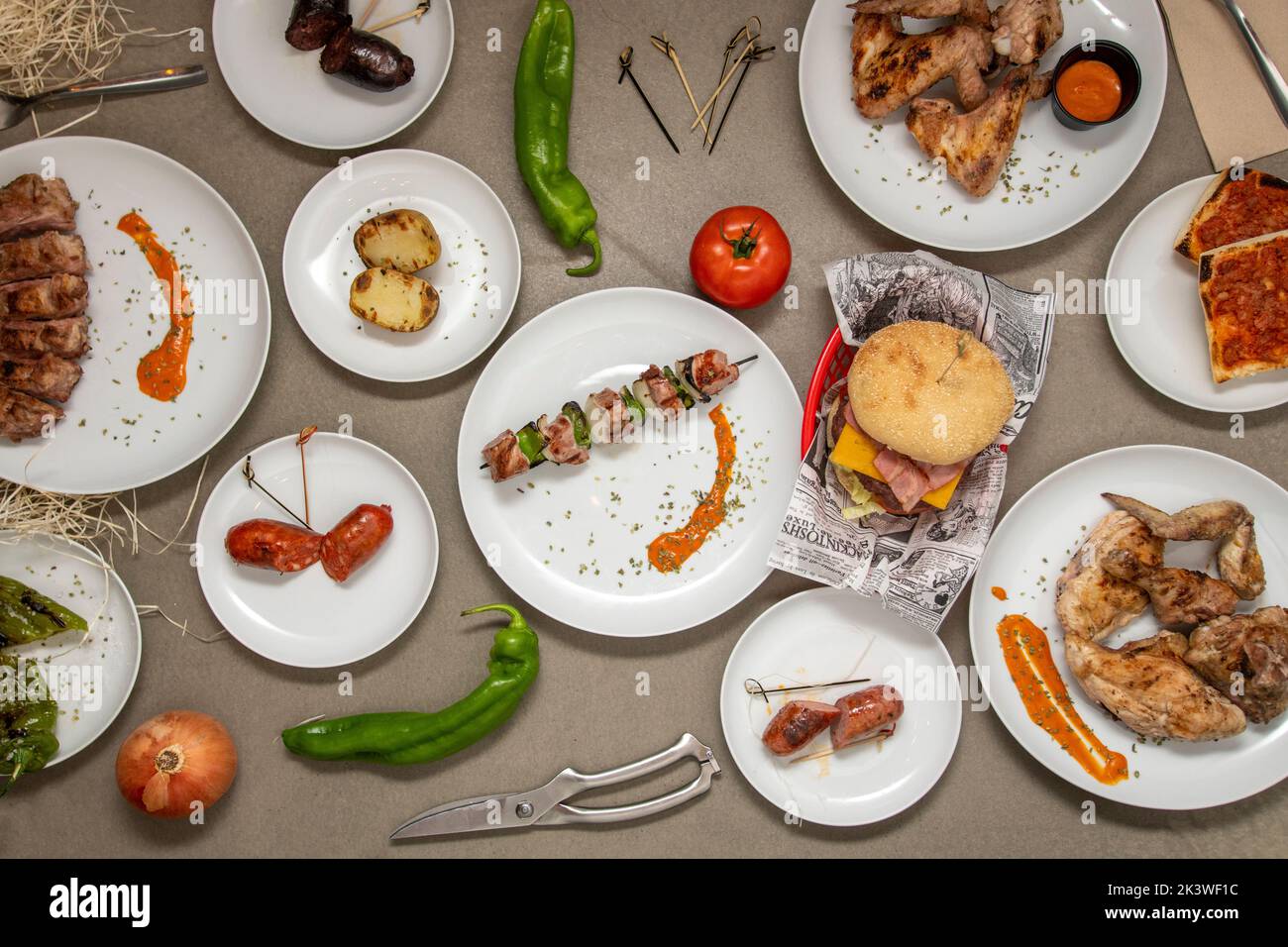 Set von weißen Tellern mit kohlegrilliertem Essen, sowohl Gemüse als auch Fleisch Stockfoto