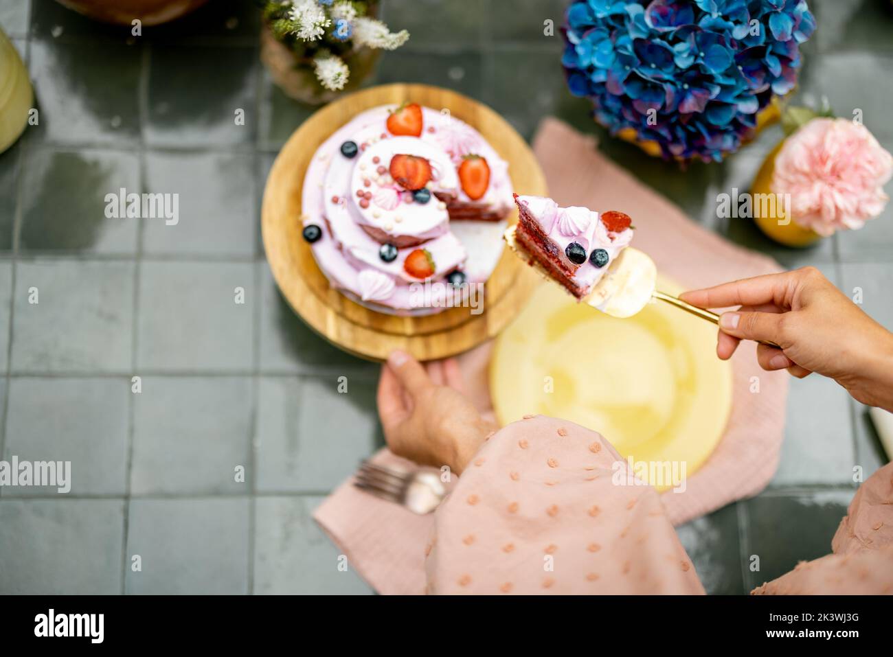 Schneiden von Beerenkäse Kuchen auf dem Tisch mit Blumen Stockfoto