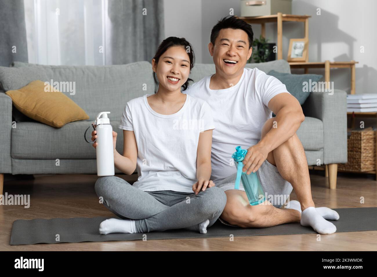 Aktive asiatische Ehegatten trainieren zusammen zu Hause, Trinkwasser Stockfoto