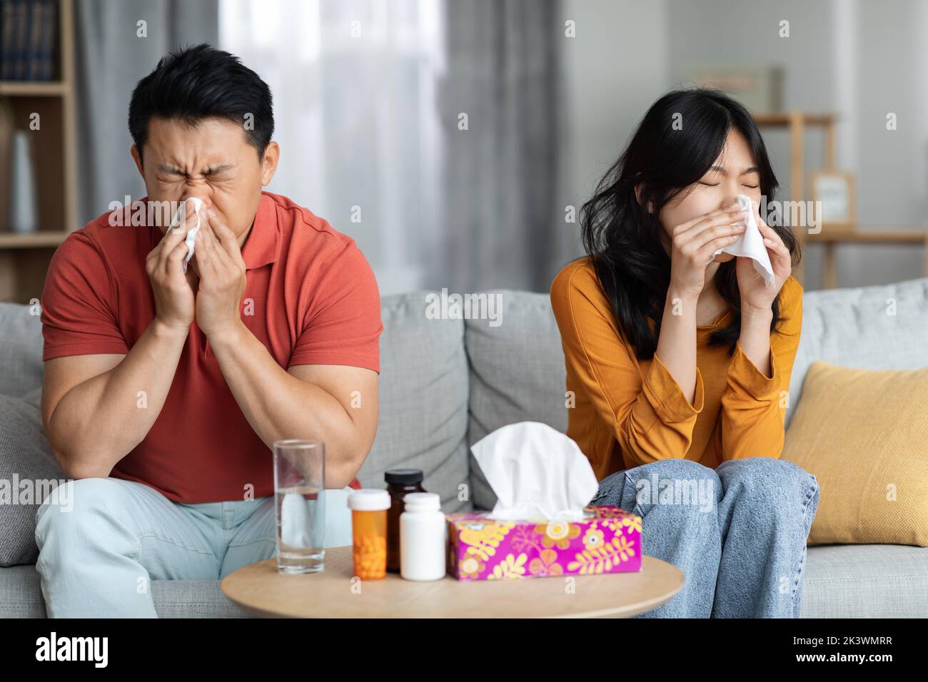 Kranker asiatischer Ehemann und Ehefrau sitzen auf dem Sofa Stockfoto