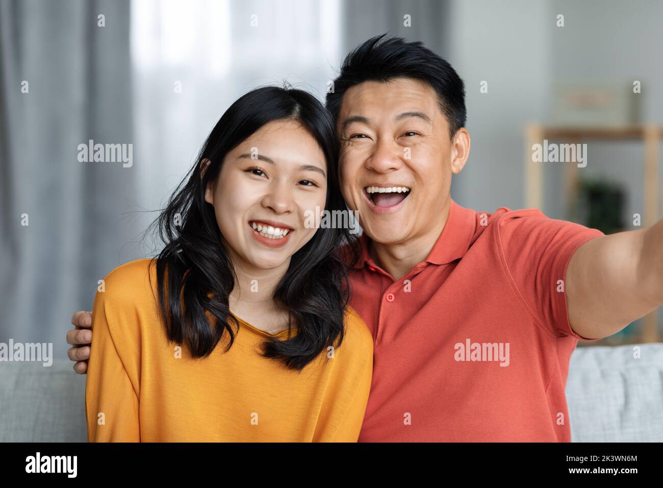 Portrait eines fröhlichen asiatischen Paares, das zu Hause Selfie nimmt Stockfoto