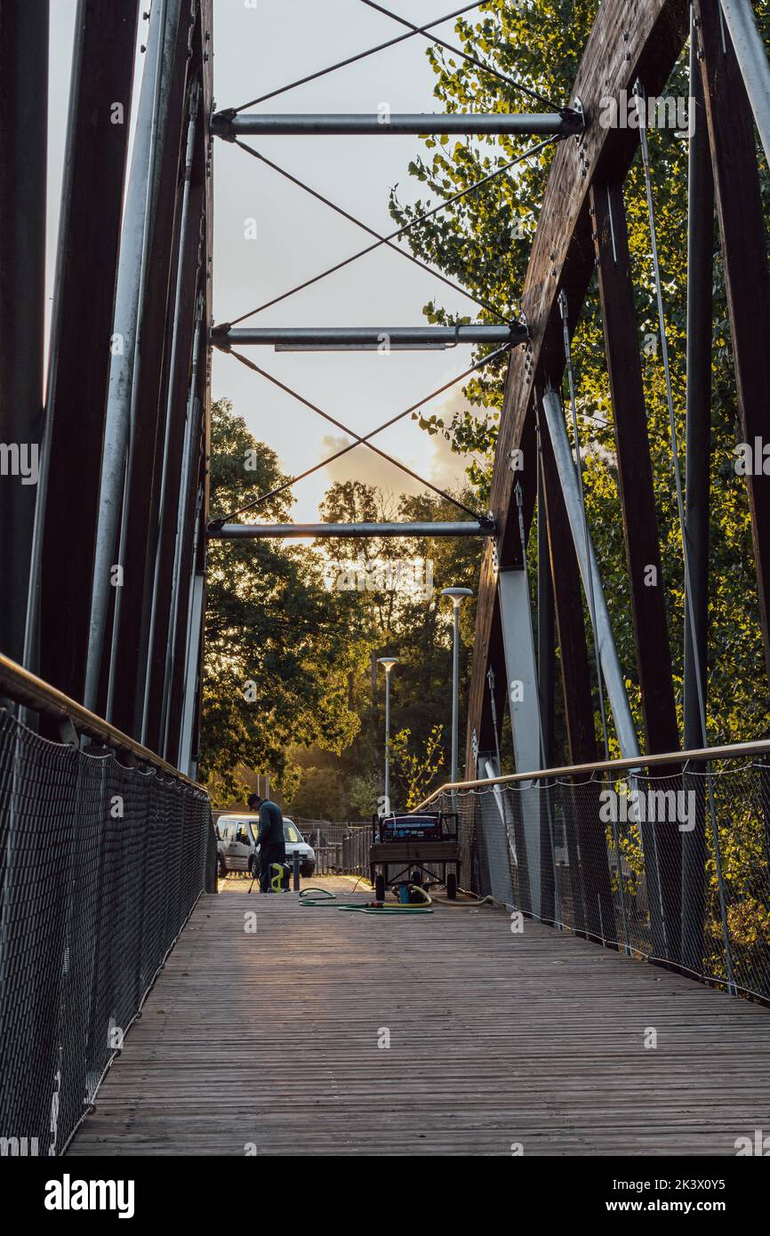 Kommunaler Mitarbeiter, der eine Holzbrücke mit einer Druckwaschmaschine reinigt Stockfoto