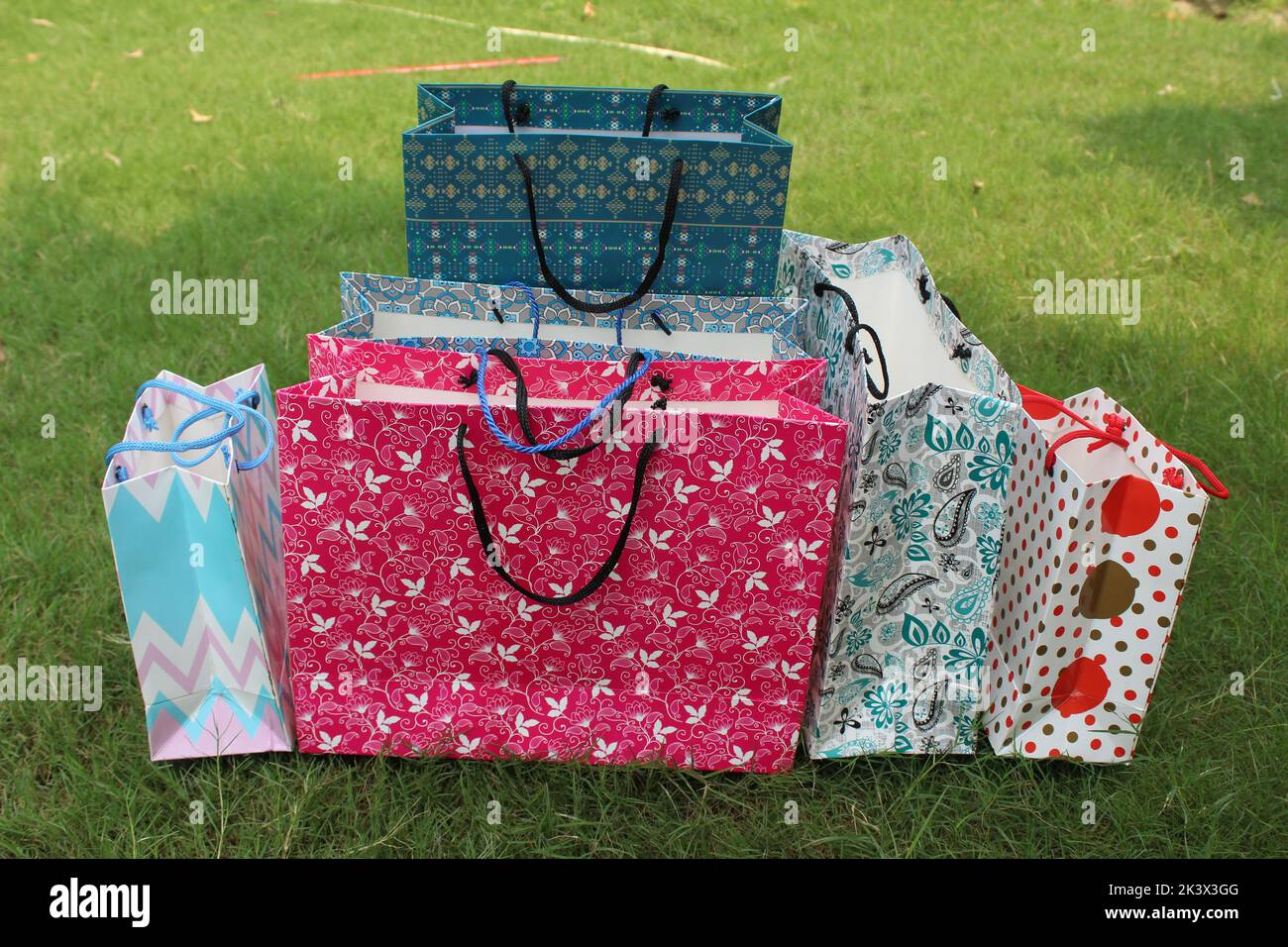 Bunte Papier Einkaufstaschen sind isoliert auf einem grünen natürlichen Hintergrund. Keine Plastiktüten nur umweltfreundliche Taschen. Stockfoto
