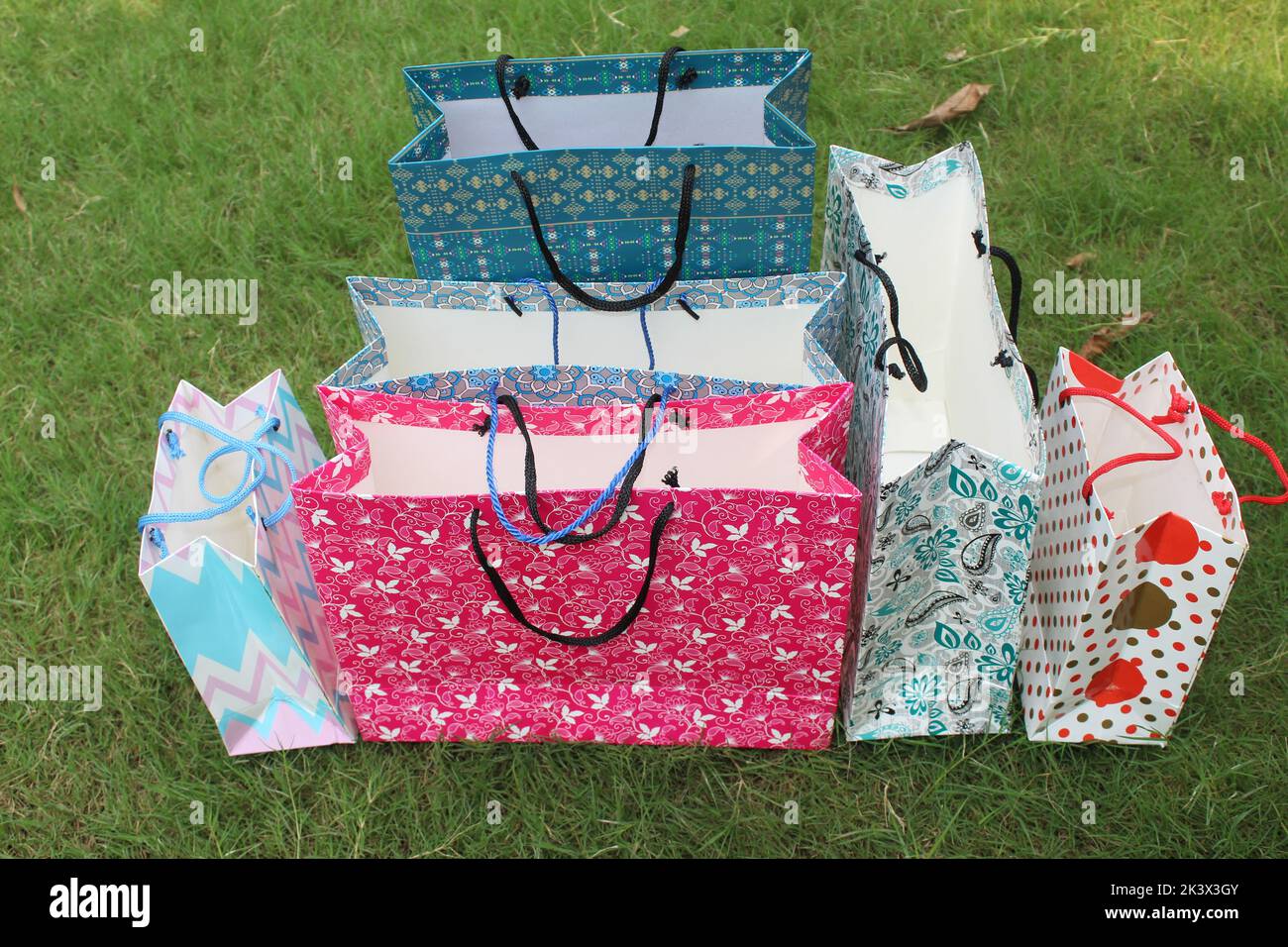 Bunte Papier Einkaufstaschen sind isoliert auf einem grünen natürlichen Hintergrund. Keine Plastiktüten nur umweltfreundliche Taschen. Stockfoto