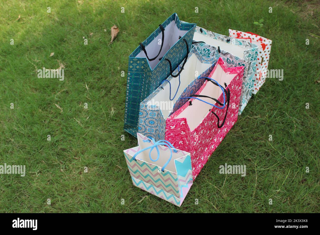 Bunte Papier Einkaufstaschen sind isoliert auf einem grünen natürlichen Hintergrund. Keine Plastiktüten nur umweltfreundliche Taschen. Stockfoto