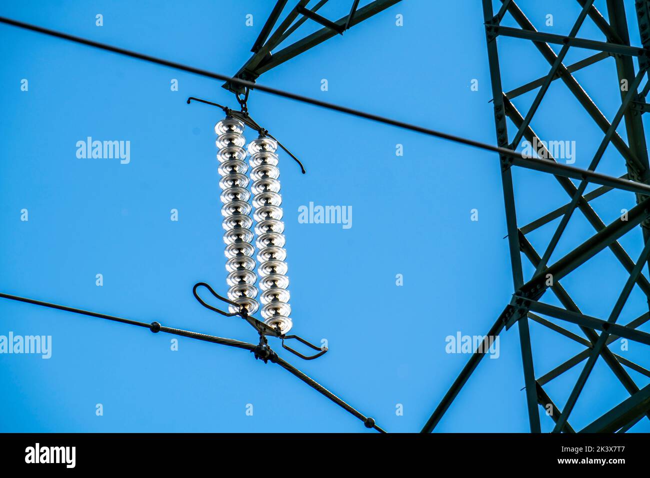 Isolatoren aus Glas an einer Hochspannungsleitung, an den Polen hängen sie als Aufhängevorrichtung zwischen dem Mast und dem stromführenden, nicht isolierten Kabel, ext Stockfoto
