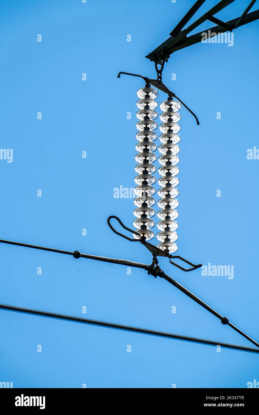 Isolatoren aus Glas an einer Hochspannungsleitung, an den Polen hängen sie als Aufhängevorrichtung zwischen dem Mast und dem stromführenden, nicht isolierten Kabel, ext Stockfoto