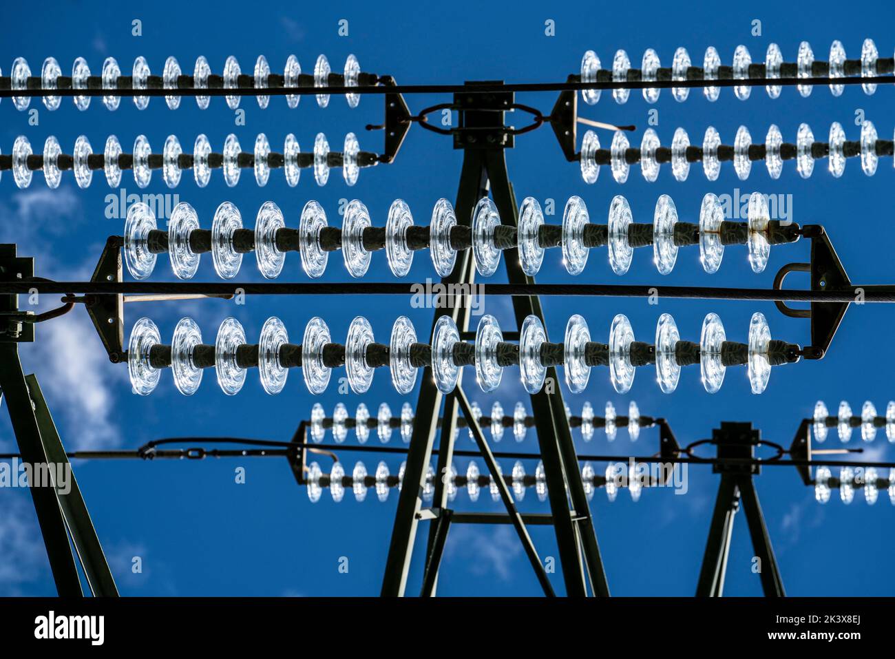 Isolatoren aus Glas an einer Hochspannungsleitung, an den Polen hängen sie als Aufhängevorrichtung zwischen dem Mast und dem stromführenden, nicht isolierten Kabel, ext Stockfoto