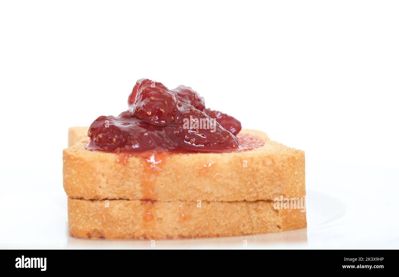 Hausgemachte Erdbeermarmelade über geschnittenem Toastbrot auf weißem Hintergrund. Frühstückskonzept. Bereich für den Kopierbereich. Stockfoto