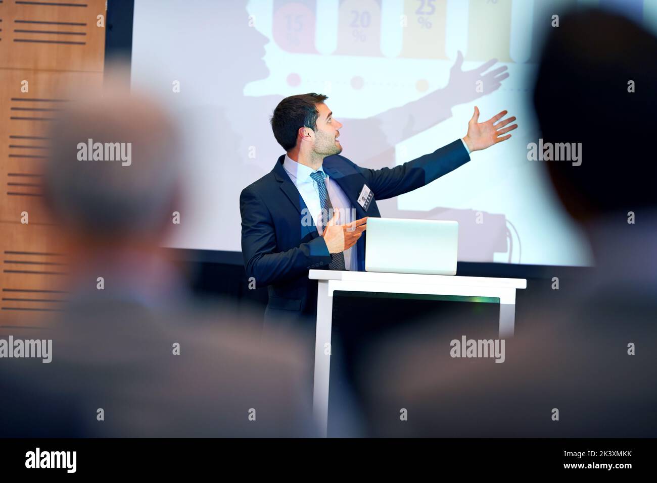 Wie Sie hier sehen können... Ein Geschäftsmann, der während einer Präsentation auf einer Pressekonferenz gestikuliert. Stockfoto