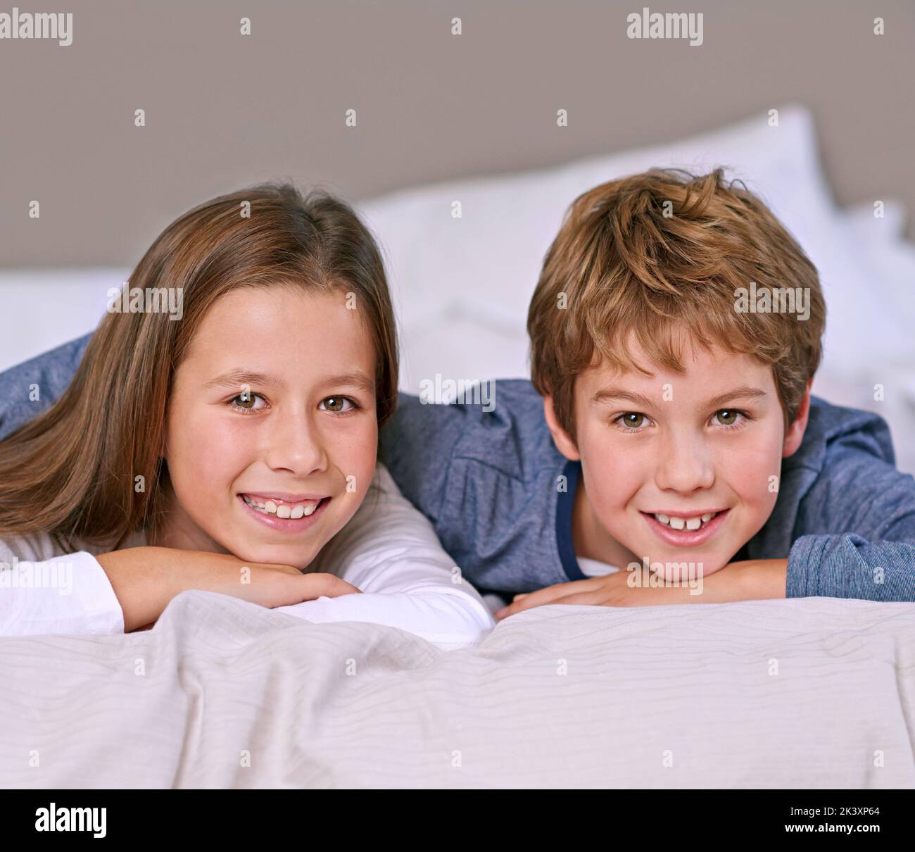Gemeinsam aufwachsen. Porträt eines Bruders und einer Schwester, die zu Hause auf einem Bett liegen. Stockfoto