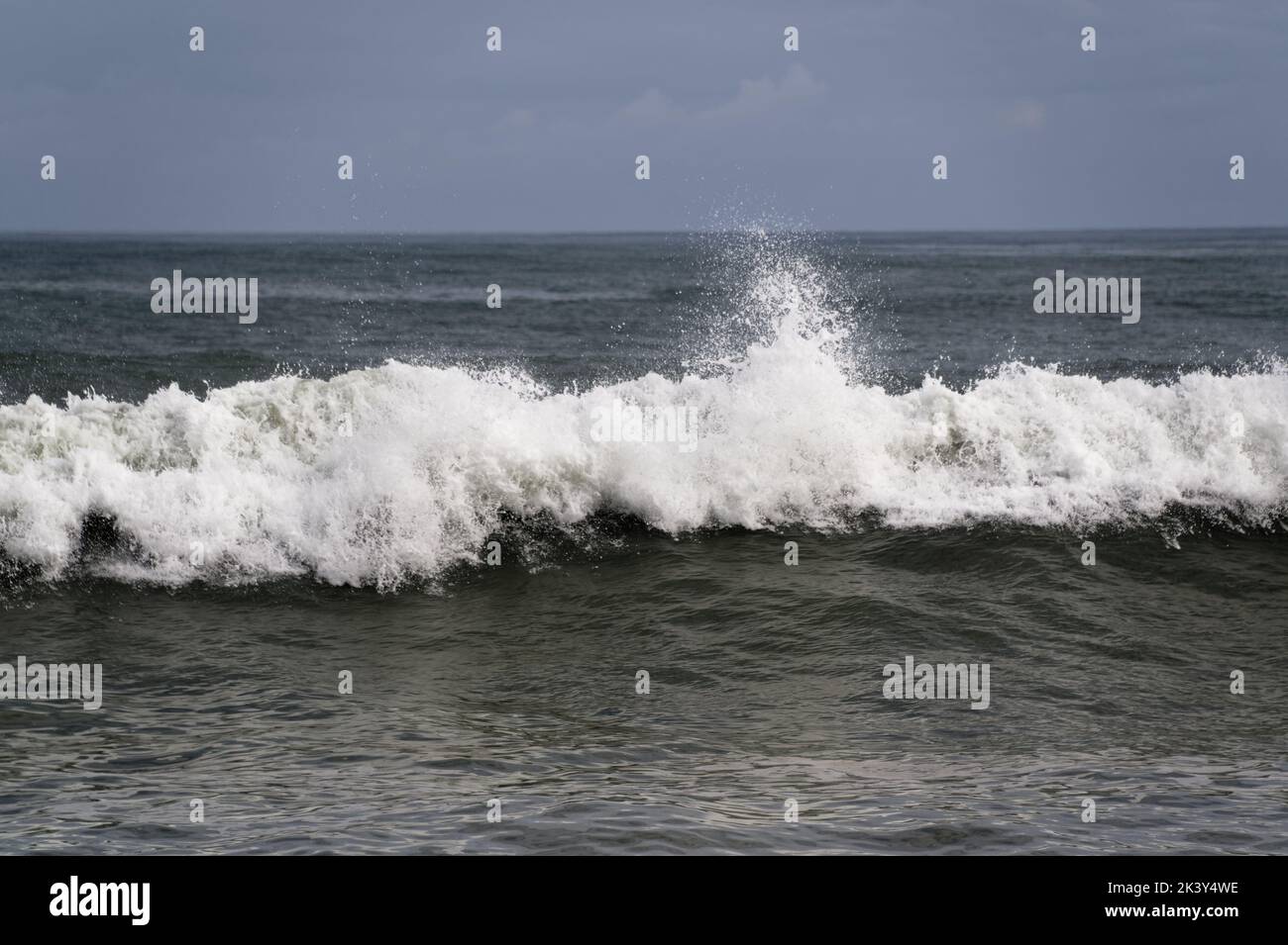 Das schaumende Weiß eines Wellengesichtes, während es zum Strand schnabelt und stolpert Stockfoto