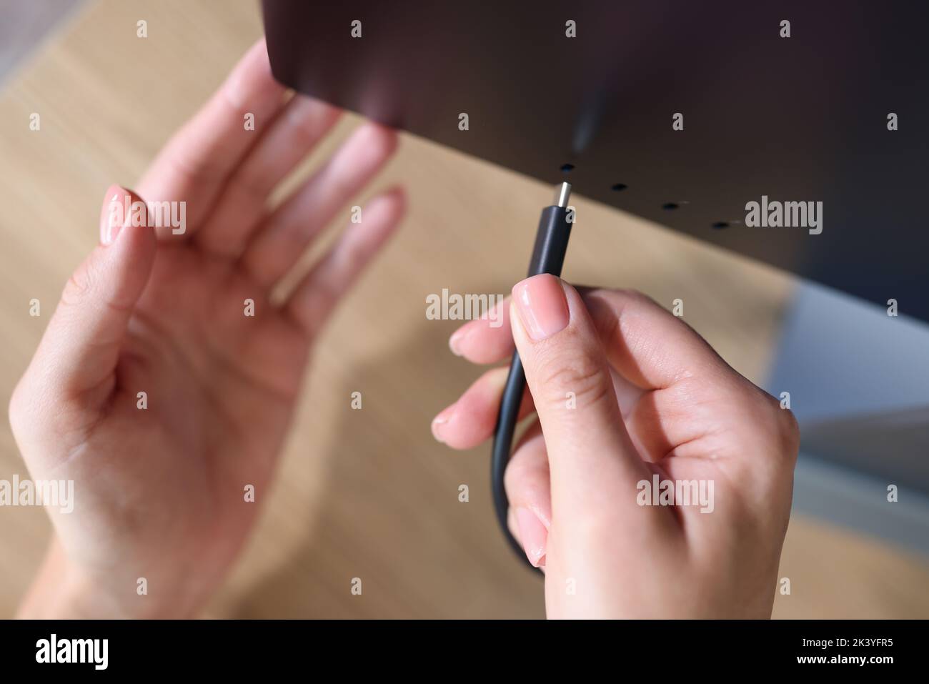 Person Hand verbindet ein schwarzes USB-C- oder Typ C-Netzkabel mit dem Computer Stockfoto