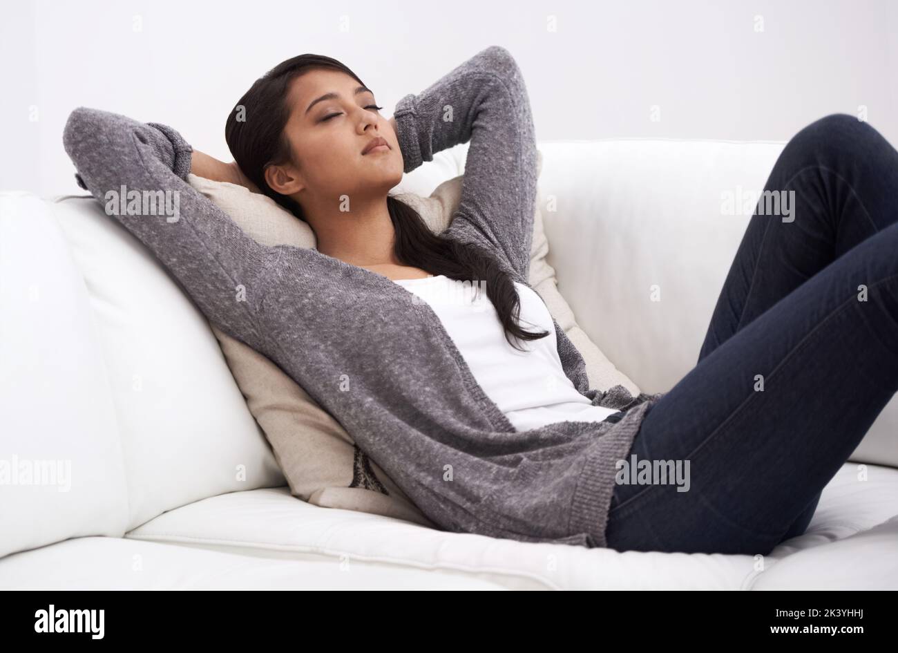 Aufladen der Batterien. Eine junge Frau, die ein Nickerchen auf ihrem Sofa macht. Stockfoto