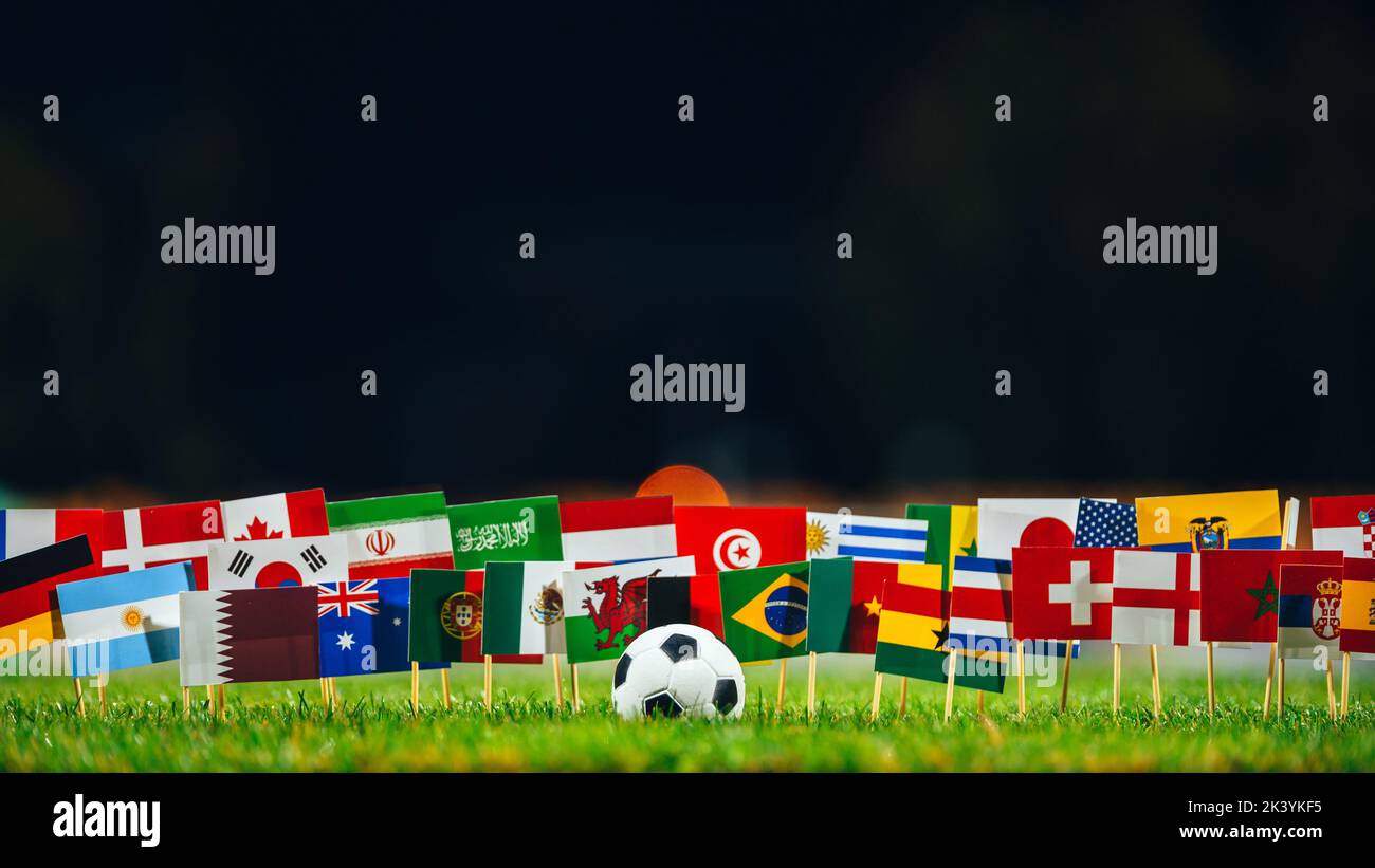 Alle 32 Flaggen und Fußball auf grünem Gras. Fußballturnier Stockfoto