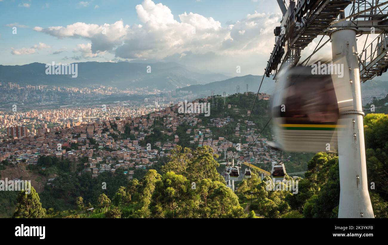 Metrocable öffentliches Nahverkehrssystem in Medellin, Kolumbien, Seilbahnen, die bei Sonnenuntergang über der Stadt fahren. Stockfoto