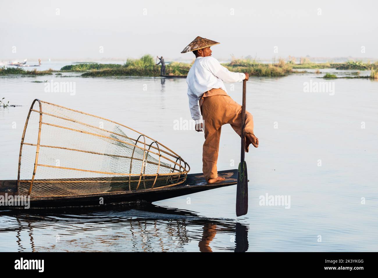 Intha Fischer Bein Rudern im traditionellen Stil auf Inle Lake, Shan Staat, Myanmar (Burma). Stockfoto
