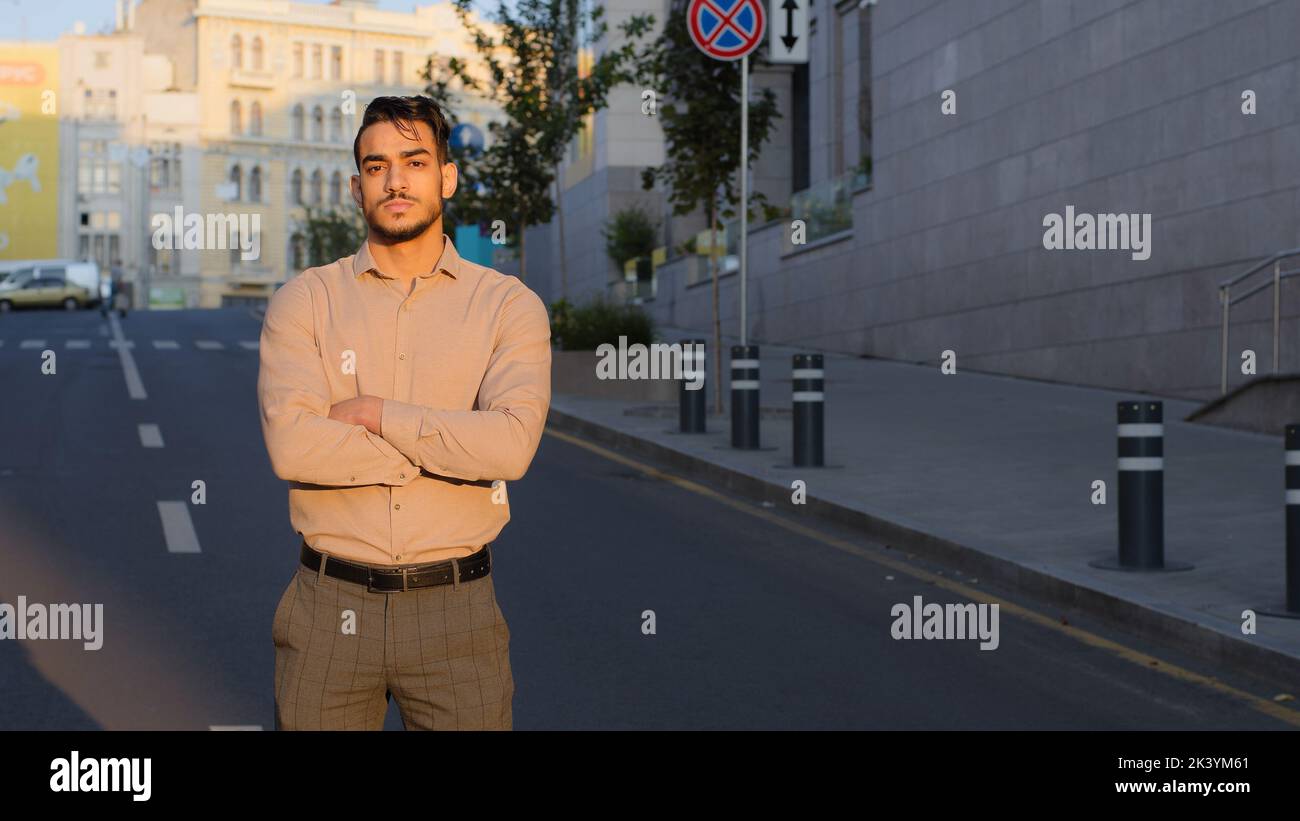 Ernsthaft selbstbewusst erfolgreicher Styling-Typ hispanic-arabisch-indianer-Geschäftsmann steht auf der Straße, überquert Waffen und überlegt sich Strategiedenken Stockfoto