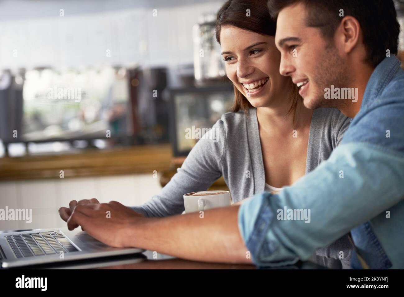 Ihre Arbeit ins Café zu bringen. Profilaufnahme eines jungen Paares, das in einem Café an einem Laptop arbeitet. Stockfoto