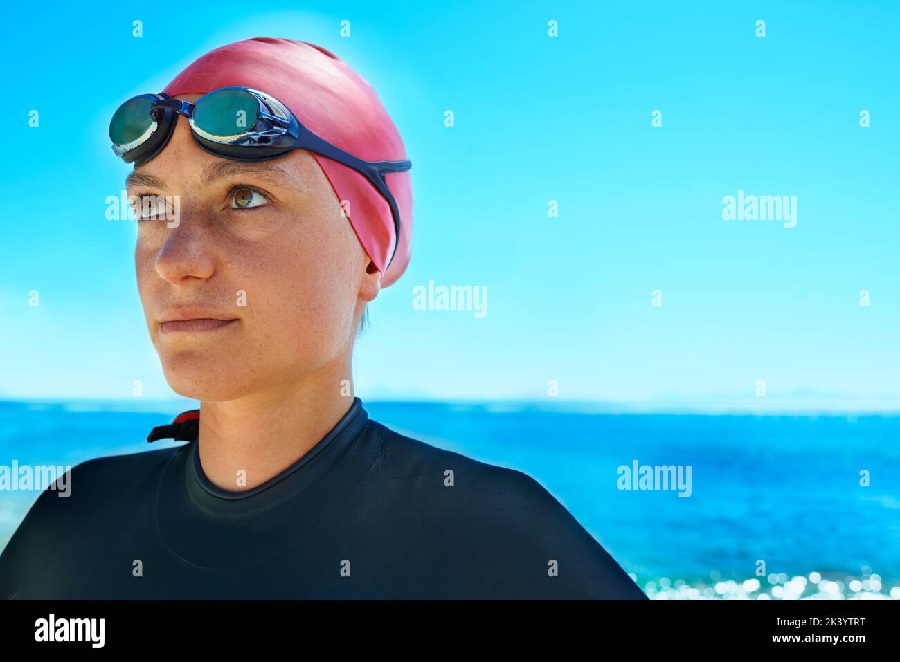 Sport im Freien. Eine junge Schwimmerin, die neben dem Meer steht und lächelt. Stockfoto