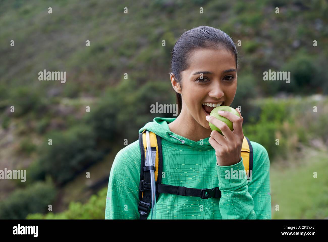 Essen die richtige Nahrung für nachhaltige Energie. Beschnittene Ansicht eines jungen Wanderers, der einen Apfel auf dem Trail genießt. Stockfoto