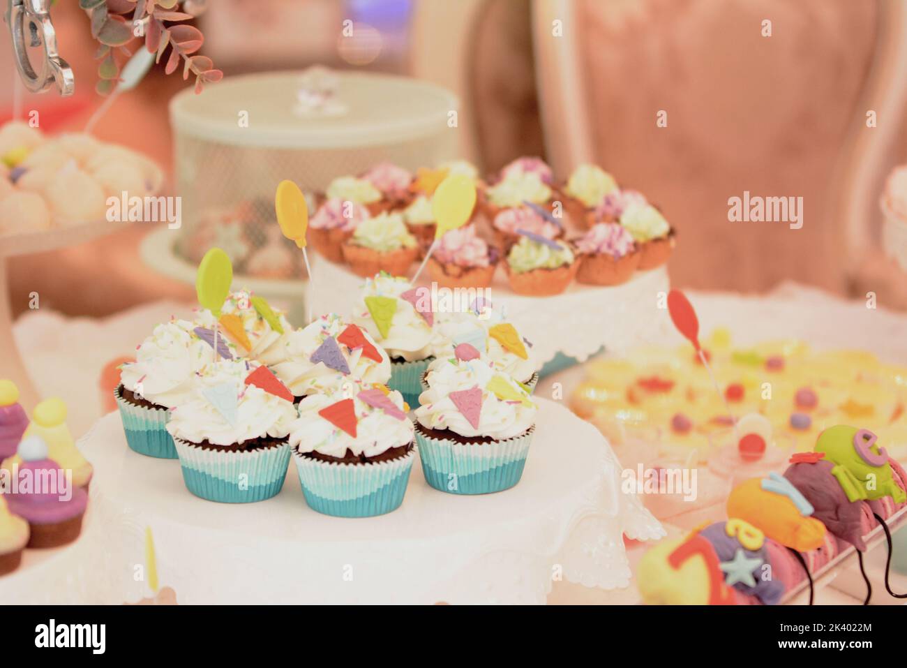 Weiße cremefarbene Muffins, verziert mit buntem dreieckigem Marzipan. Süßigkeitenbar Stockfoto