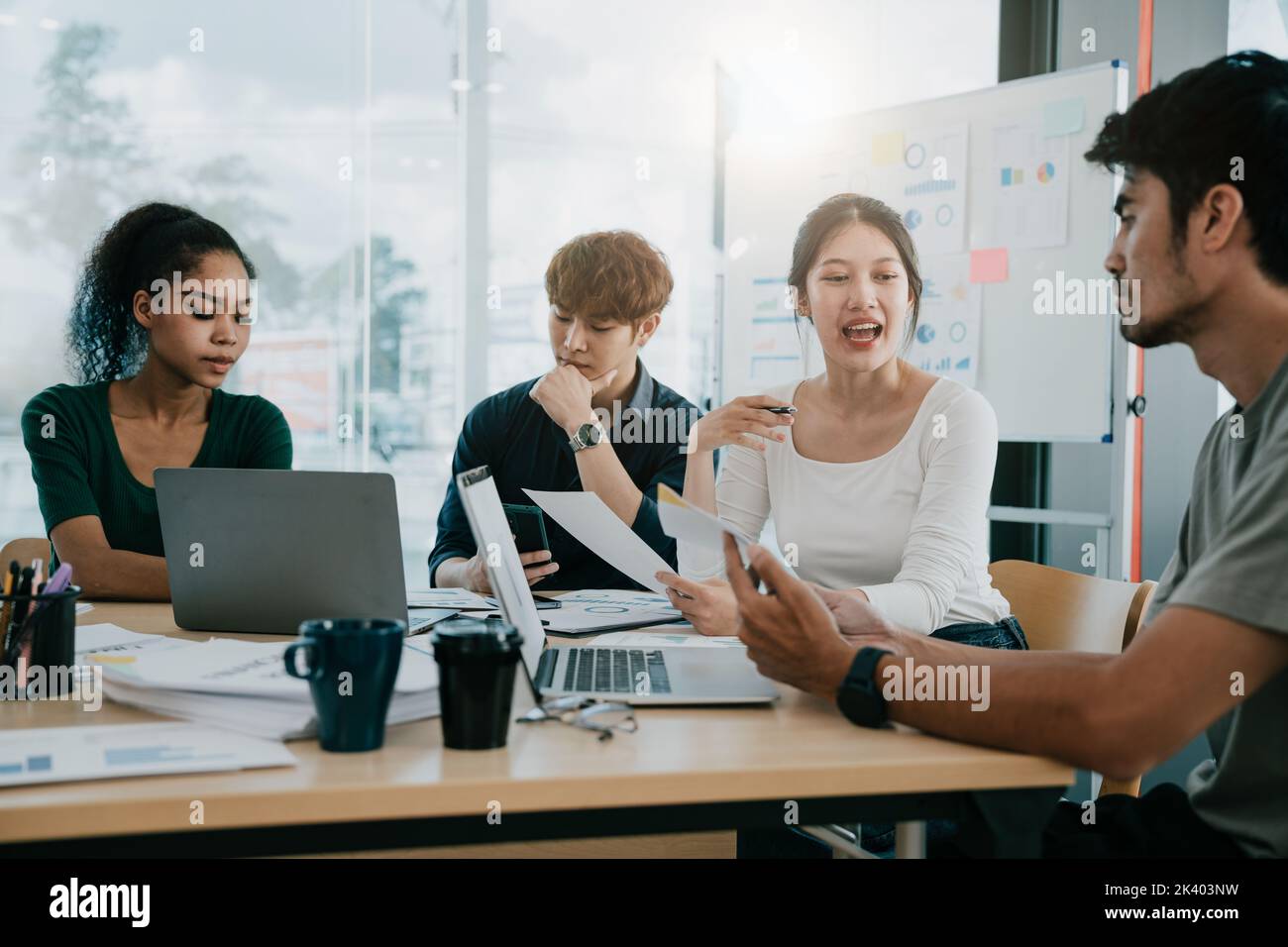 Kreatives Diversity-Business-Team am Tisch in einem modernen Startup-Büro. Sprecherin bietet eine tolle Idee und das Team unterstützt Stockfoto