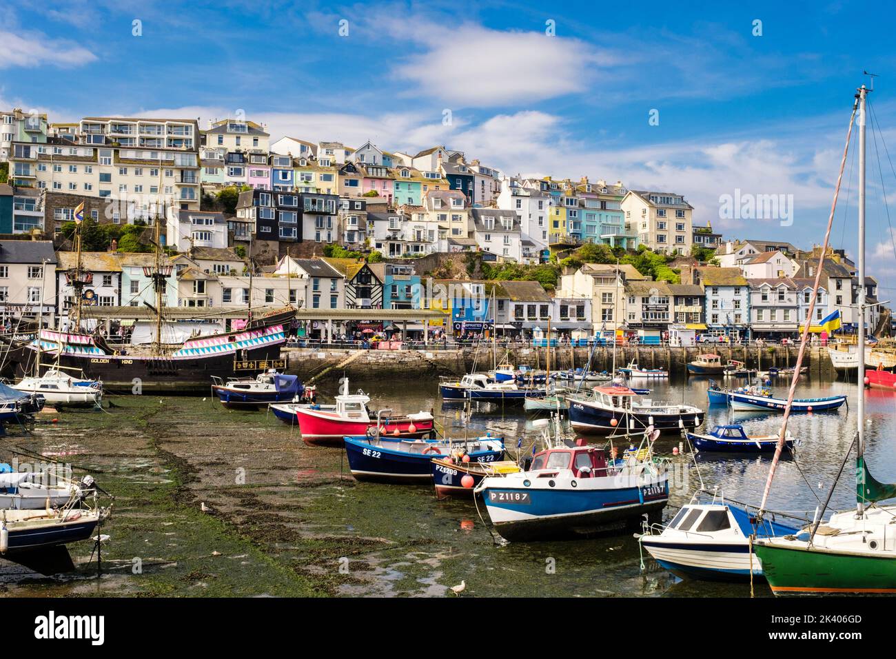 Farbenfrohe Häuser und Geschäfte mit Blick auf den Innenhafen und kleinen Booten, die vor Anker liegen. Brixham, Devon, England, Großbritannien Stockfoto