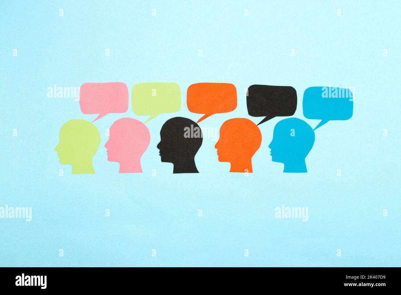 Bunte Köpfe mit Blasen oben, sozialer Kommunikationshintergrund, flaches Lay, Papierhandwerk Stockfoto