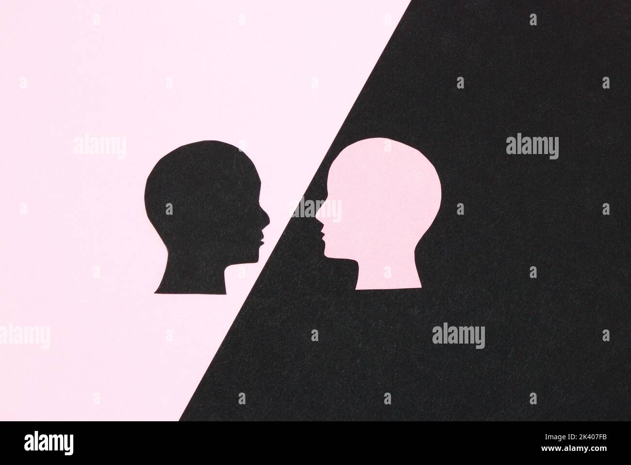 Schwarzer und rosafarbener Hintergrund, schwarzer Kopf auf dem rosa Teil, Blick auf den rosa Kopf und den schwarzen Teil, Geschäftskommunikation Stockfoto