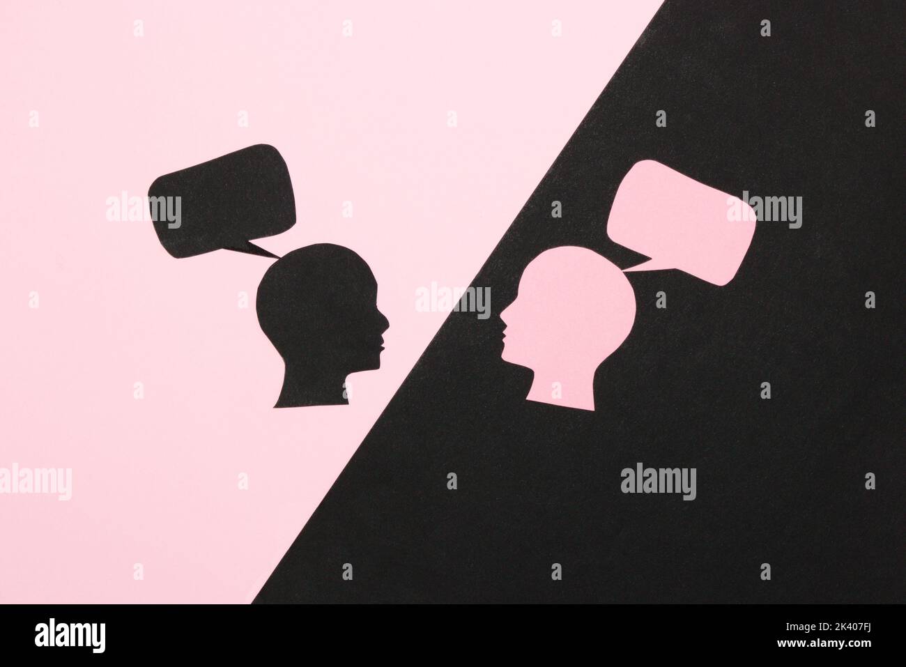 Schwarz-rosa Hintergrund, mit einem schwarzen Teil rosa Kopf mit einer Sprechblase, auf dem rosa Teil ein schwarzer Kopf mit einer Sprechblase, Kommunikation kreativ Stockfoto
