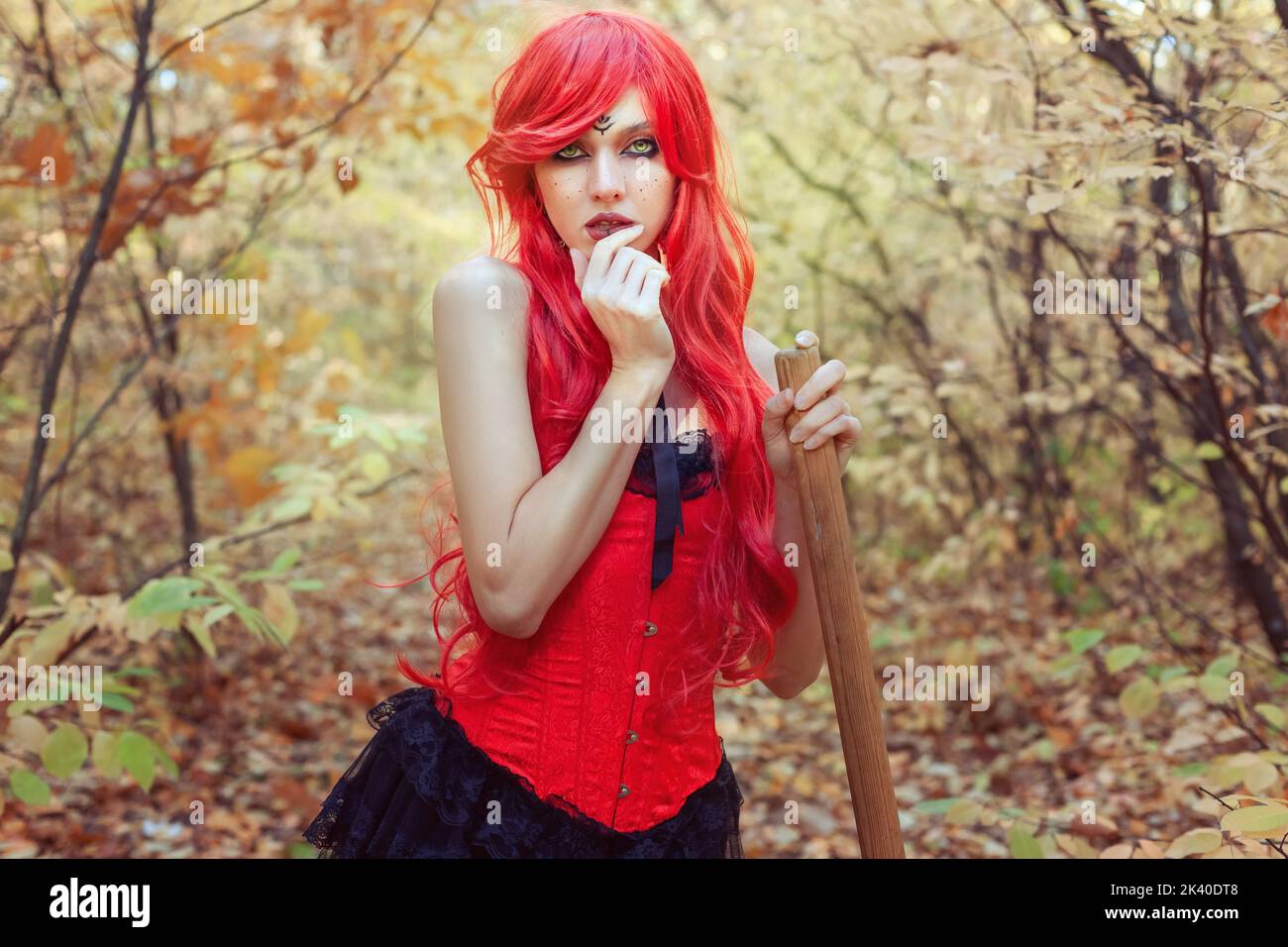 Junge und schöne Hexe mit Besen im Herbstwald. Stockfoto