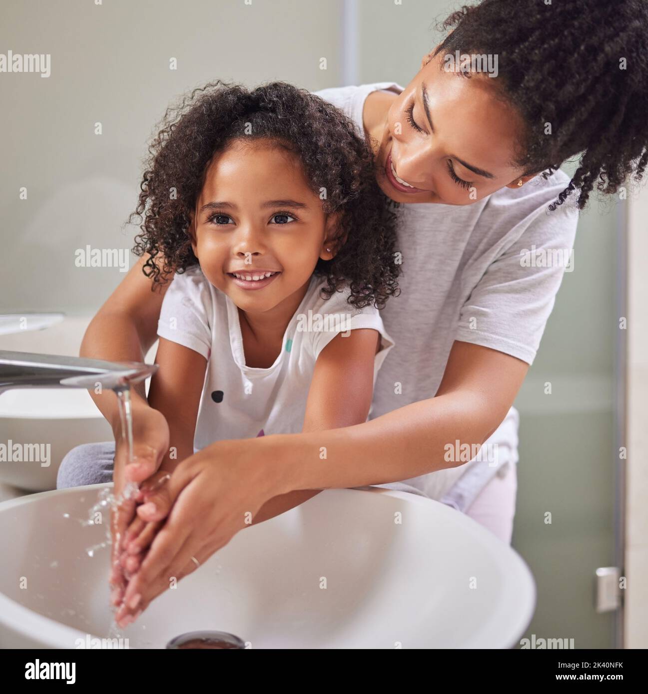 Mutter, Mädchen und Badezimmer waschen sich die Hände für Gesundheit und Hygiene im Haus. Kind, Wasser und Mutter lehren, Keime zu waschen, auf Handflächen und Fingern zu Stockfoto