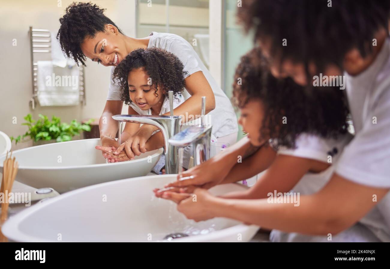 Mutter und Kind im Bad waschen Hände, putzen und Hygiene zu Hause lernen. Junge Mutter mit Mädchen, die ihr beibringt und ihr hilft, sich die Hände zu waschen Stockfoto