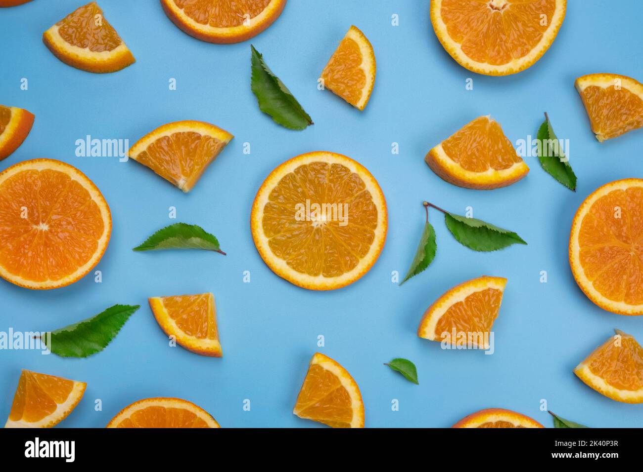 Hintergrund mit Folien aus Orange und Blättern auf blauem Hintergrund, trendy Sommer, fruchtiger Hintergrund. Stockfoto