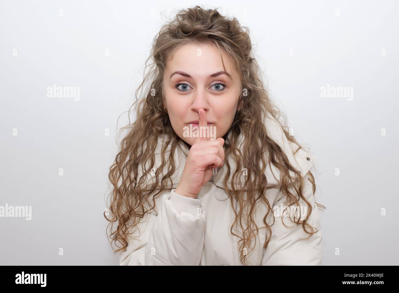 Frau macht eine leisende Geste, indem sie ihren Finger auf ihre Lippen hebt, während sie um Schweigen bittet oder um deine Hilfe bei der Aufbewahrung eines geheimen Stockfotos Stockfoto