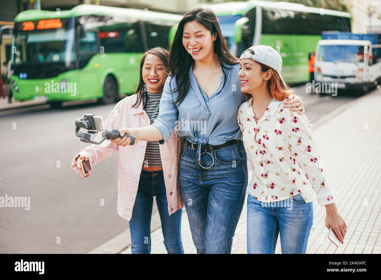 Glückliche asiatische Mädchen Streaming-Video mit Handy an der Stadt Busbahnhof - Weiche Fokus auf Mitte Mädchen Gesicht Stockfoto