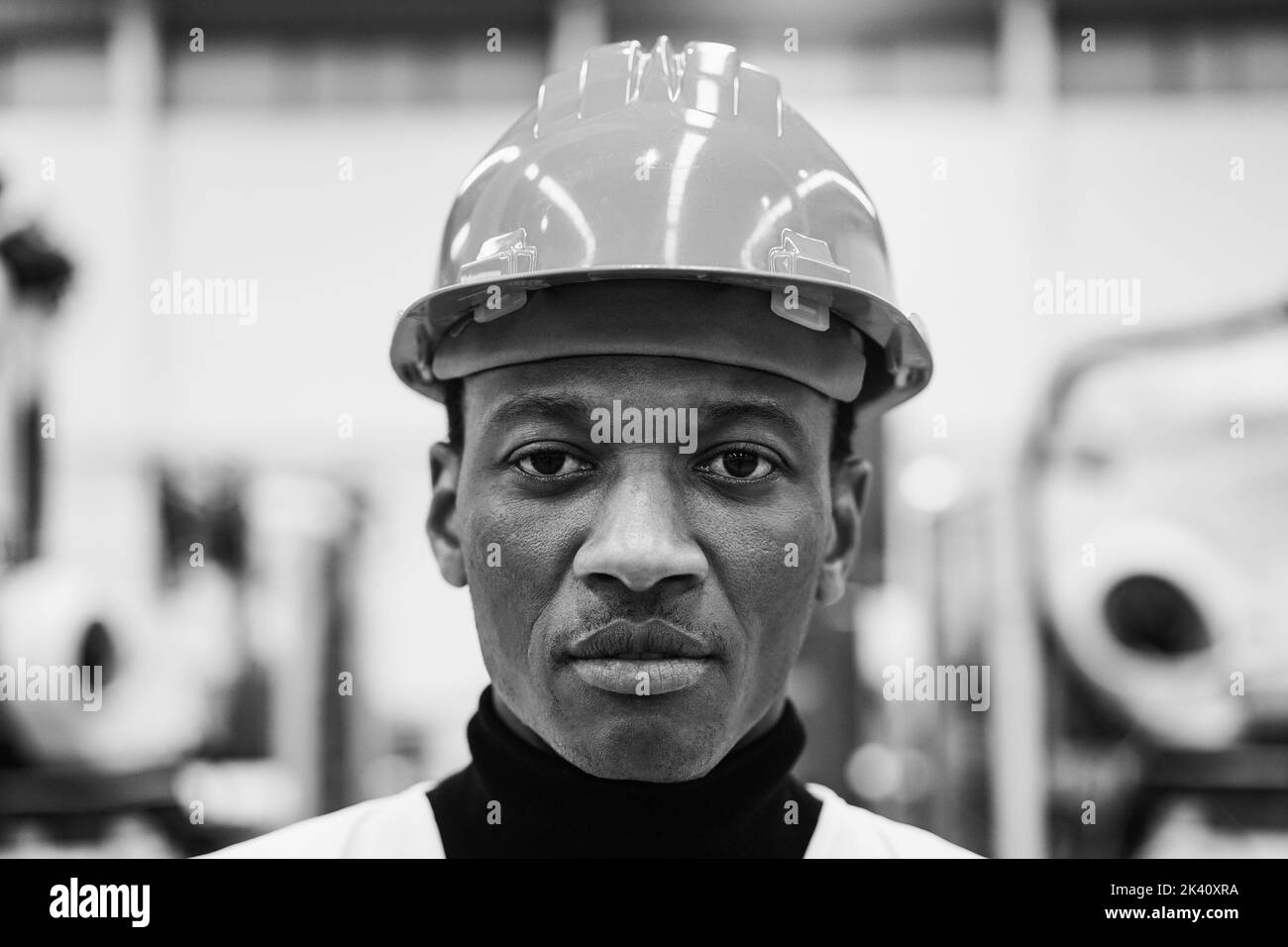 Afrikanischer Ingenieur, der in der Roboterfabrik arbeitet - Fokus auf Gesicht - Schwarz-Weiß-Schnitt Stockfoto
