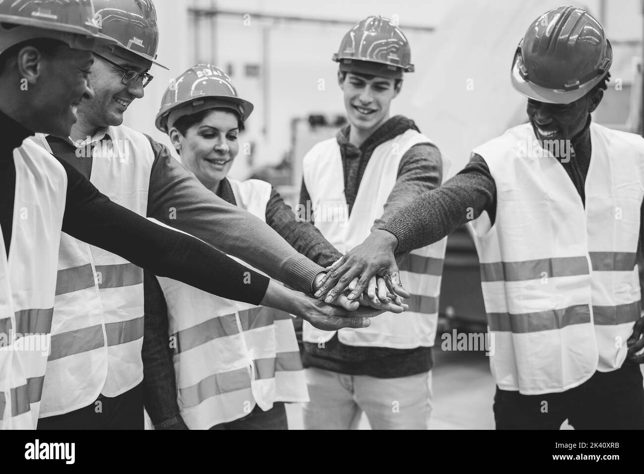 Multirassische Ingenieure stapeln Hände in Roboterfabrik - Fokus auf Hände - Schwarz-Weiß-Schnitt Stockfoto