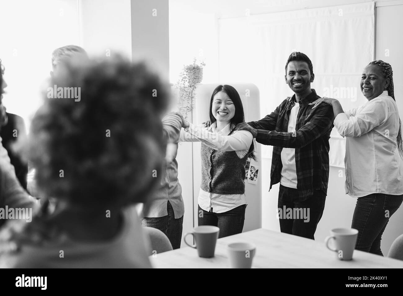 Multirassische glückliche Freunde, die Spaß beim Tanzen in der heimischen Küche haben - Schwerpunkt auf dem indischen Männergesicht - Schwarz-Weiß-Schnitt Stockfoto
