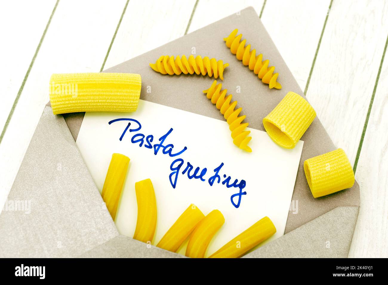 Umschlag mit Text Pasta Grüße und verschiedene Arten von rohen ungekochte Pasta auf weißem Holz Hintergrund wie grafische Konzept von Pasta-Essen Stockfoto